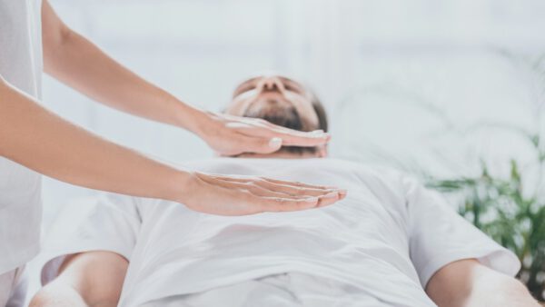 cropped shot of bearded man receiving reiki healing session above stomach